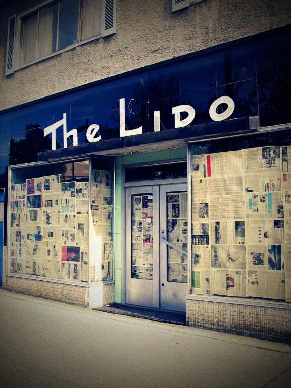 Exterior of The Lido store on Broadway in Vancouver showing windows covered in newspapers.